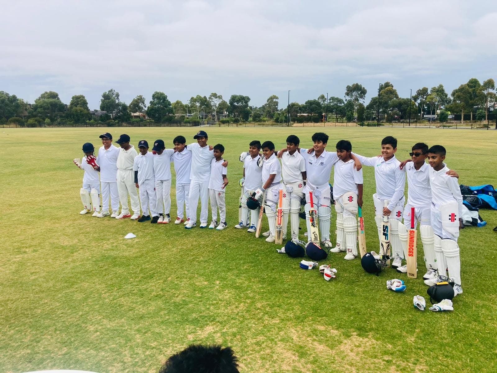 Junior cricket lineup in whites on the oval